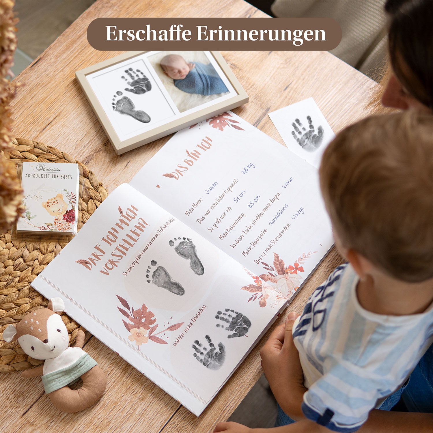 Mutter und Kind erstellen ein Erinnerungsbuch mit Babyhand- und Fußabdrücken, neben einem Abdruckset für Babys und einem gerahmten Foto mit Hand- und Fußabdrücken.